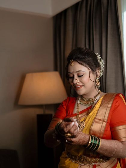 A candid shot of the Maharashtrian bride getting ready, her smile lighting up the room as she adjusts her bangles.