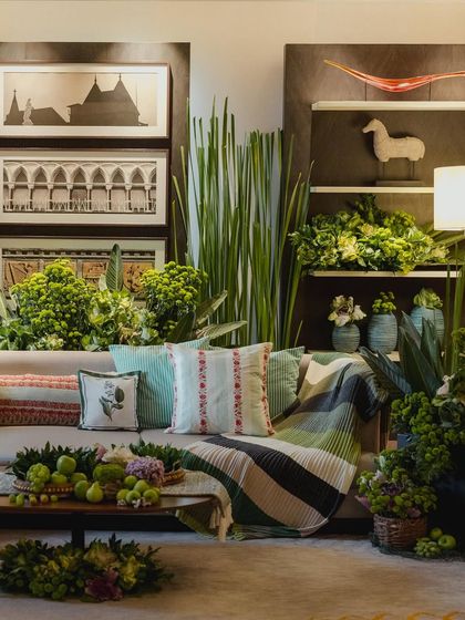 A cozy lounge area from the green-themed Mehendi, filled with lush plants, green apples, and custom-printed cushions.
