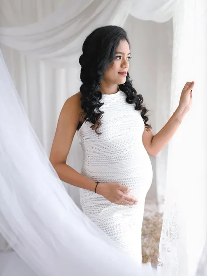 Looking out the window, as if dreaming of the future. This is a classic, contemplative pose that captures the quiet moments of pregnancy.