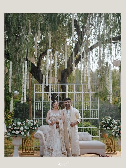 A grand portrait of the engaged couple under a beautifully decorated tree, looking regal and happy.