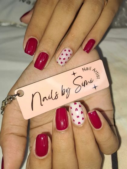 A cute and simple design with red nails and a white accent nail covered in tiny red hearts.