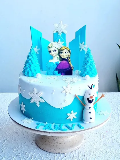 A full view of the blue Frozen cake, showing the Olaf topper and snowflake details.
