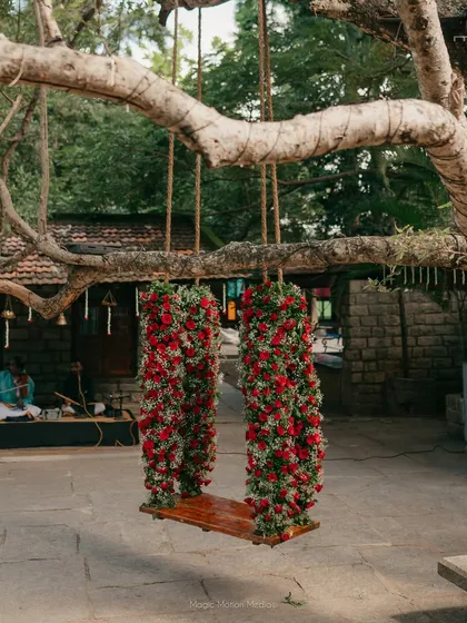 A swing lavishly decorated with deep red roses, perfect for a bold and romantic wedding theme.