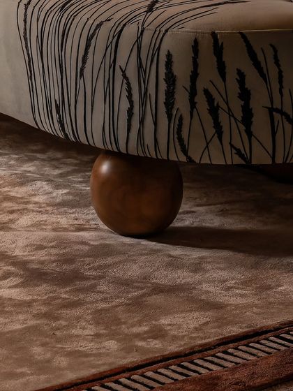 Every detail is considered, right down to the feet of the furniture. Here, the custom-printed fabric of the sculptural armchair meets a solid wood bun foot, resting on a plush, textured rug. This interplay of materials is central to our design approach.