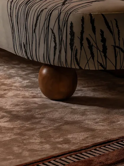 The beauty is in the combination of textures. Here, a custom sofa with delicate embroidery rests on a solid wooden ball foot, all set against a deeply textured rug. It's a small moment that reveals a larger story of layered design.