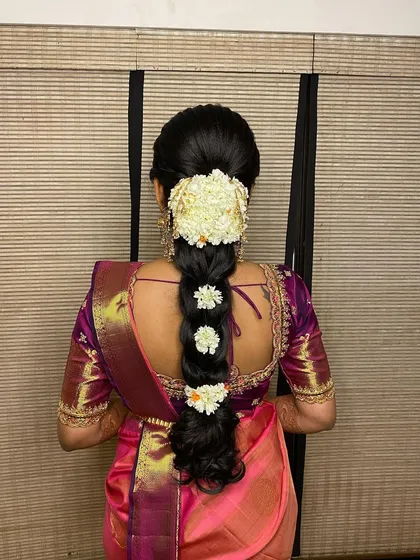 An engagement look featuring a messy braid adorned with jasmine flowers. The textured plait gives a modern feel to the otherwise traditional hairstyle.