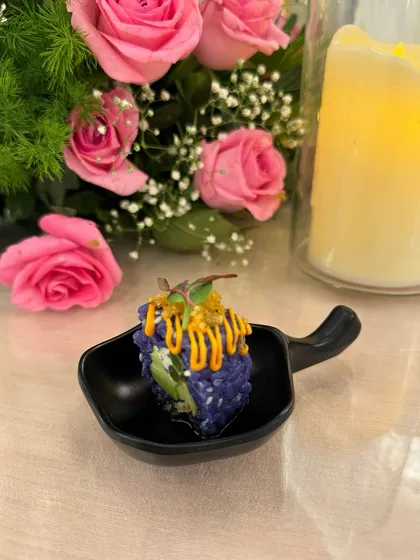 A visually striking appetizer made with blue pea flower rice and avocado, drizzled with a tangy sauce. This dish showcases our flair for creating unique and colourful culinary experiences.