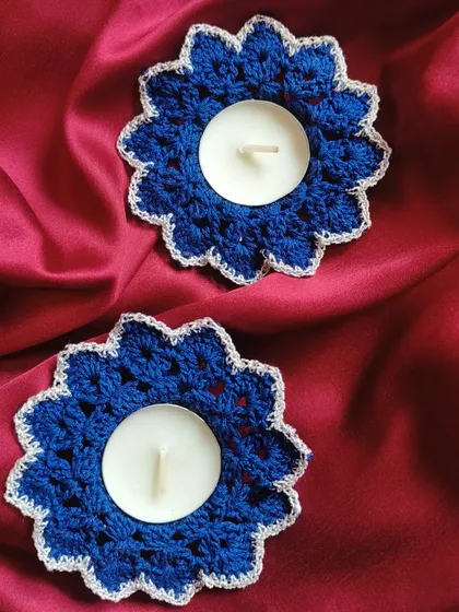 A pair of royal blue crochet diya coasters with a silver-white trim. The vibrant color adds a modern pop to traditional Diwali decorations.