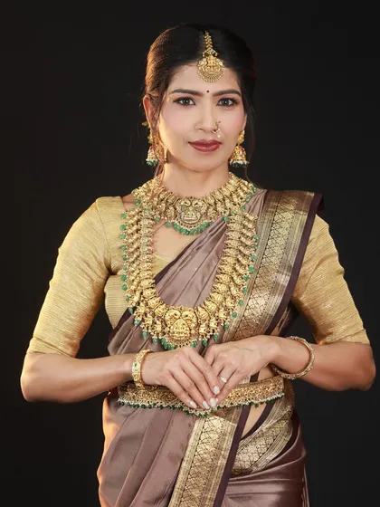 This is a classic studio portrait focused on traditional attire. The clean black background and soft lighting bring all the attention to the model's expression and the beautiful details of the temple jewellery set.