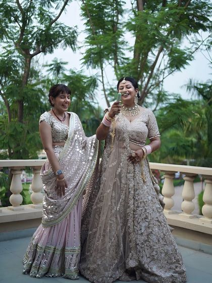 A candid moment of a bride sharing a laugh with her sister or friend on a balcony.