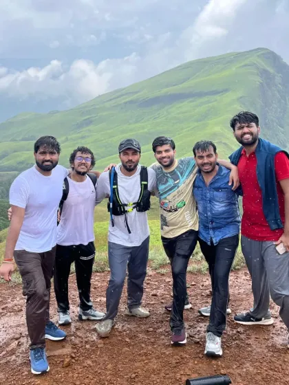 A small group of friends at the summit of Ettina Bhuja, with the unique peak visible in the background.