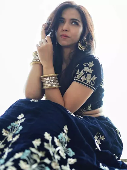 A bright, high-key portrait where the model is looking up, creating a hopeful and radiant mood. This shot showcases her full ethnic outfit, including the embroidered lehenga and traditional jewelry, against a clean, white background.
