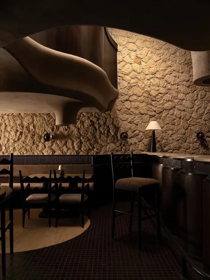 A corner detail where the fluid forms of the ceiling meet the rugged texture of the stone wall. This is where the core concept of the design, the interplay of raw and refined, is most apparent.
