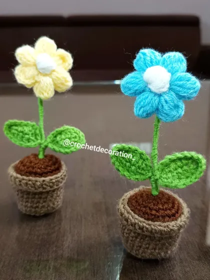A close-up of the yellow and light blue puffy flower pots, showing the texture of the crochet work.