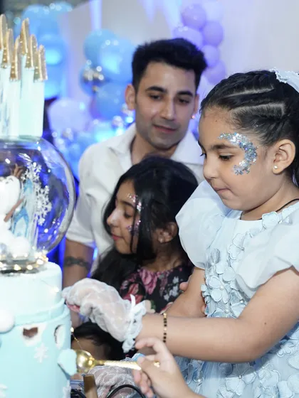 The birthday girl carefully cuts her spectacular 'Frozen' themed cake, a highlight moment of any party.
