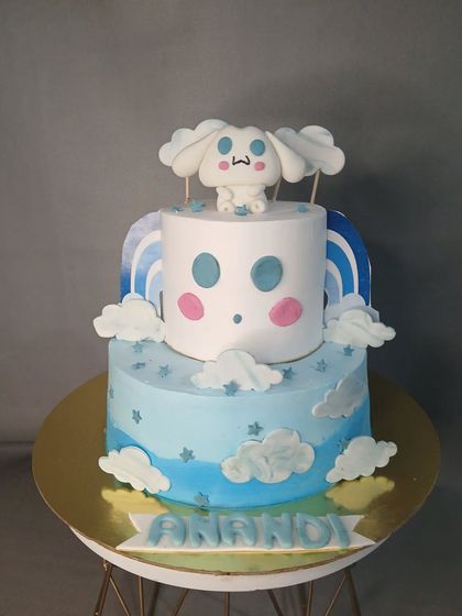 A sweet two-tiered Cinnamoroll cake, with the cute character sitting on a cloud. The pastel blue and white colors create a dreamy sky theme.