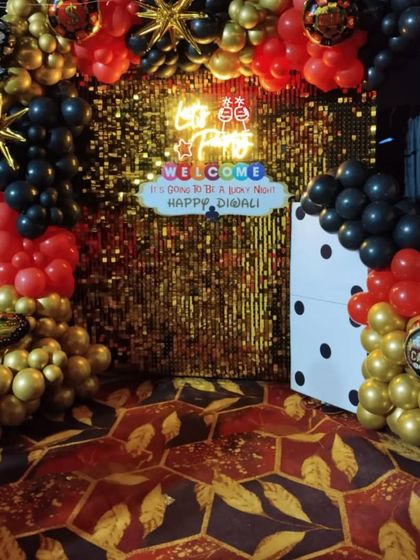 The full casino-themed backdrop for a Diwali party, featuring a gold sequin wall, a balloon arch, and a large domino prop.