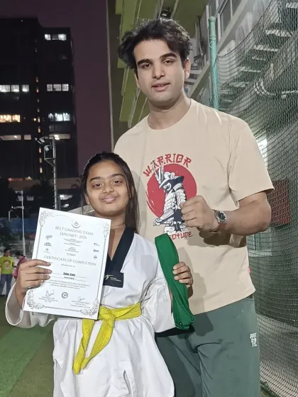 A student receives her certificate and new belt after a successful grading exam. A well-deserved promotion.