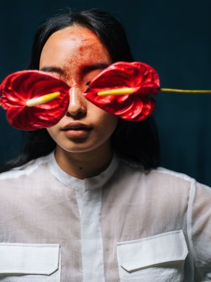 A conceptual and artistic portrait for sustainable brand Label Rama. The use of anthurium flowers as glasses is a bold creative choice designed to be memorable and thought-provoking.