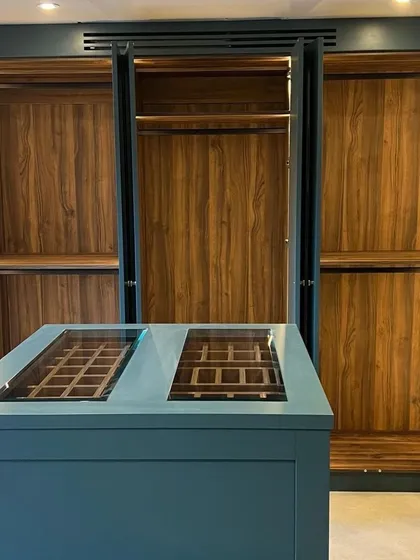 For this spacious walk-in closet, we built a custom central island in a striking teal PU finish. The island features glass-top display drawers, perfect for organizing watches, ties, and accessories, adding another layer of functionality and style.