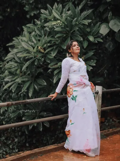 A full-length portrait on a bridge with lush greenery in the background, capturing the peaceful atmosphere of the temple grounds.