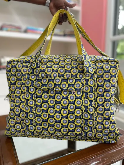 The reverse side of the yellow quilted travel bag, showing a different but complementary floral pattern.