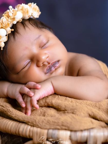 A close-up on the newborn's face, adorned with a delicate floral headband, highlighting their peaceful sleep.