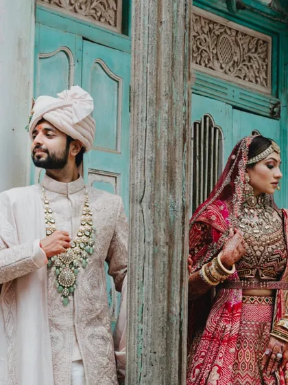 A stylish, editorial-style shot of the couple, showcasing their stunning outfits and the unique character of the location.