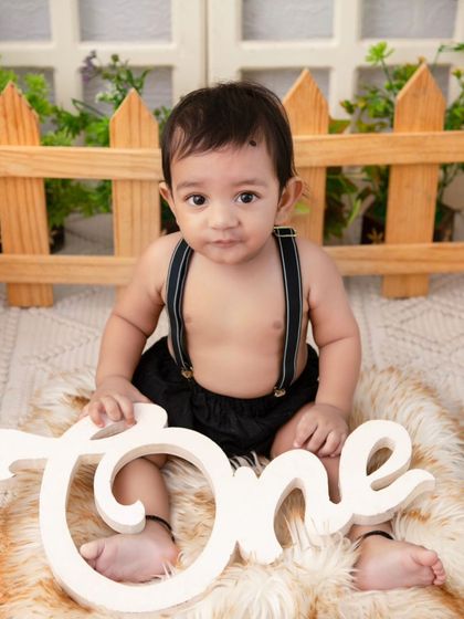 A simple and sweet portrait in a rustic setting. The 'One' sign and furry rug are perfect props for a first birthday shoot.