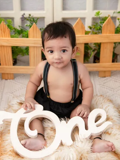 A simple and sweet portrait in a rustic setting. The 'One' sign and furry rug are perfect props for a first birthday shoot.