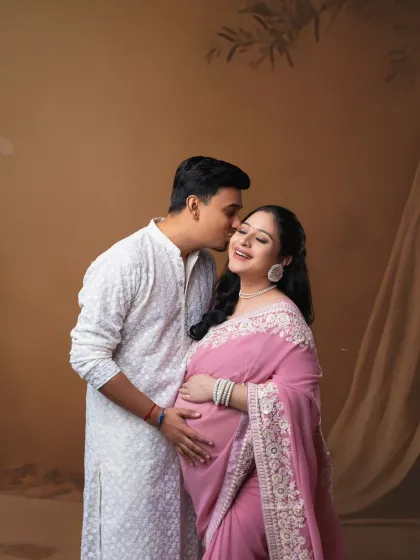 A sweet kiss and a happy smile. This couple's portrait, with the mother-to-be in a beautiful saree, is full of warmth and traditional elegance.
