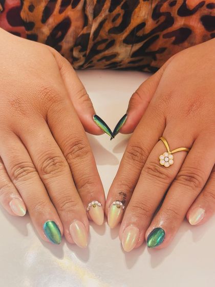 A chic combination of cat-eye green polish and a pearly nude, accented with rhinestones at the cuticle.