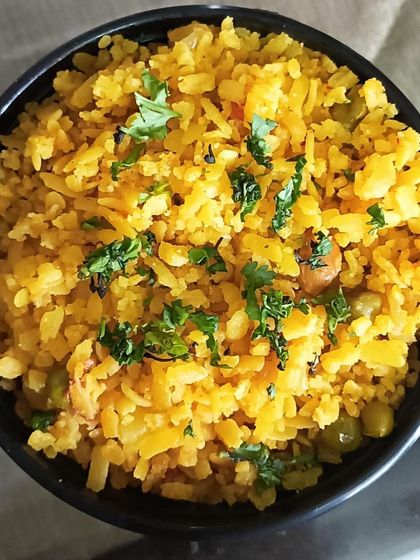A bowl of light and fluffy Poha, tempered with mustard seeds and garnished with coriander.