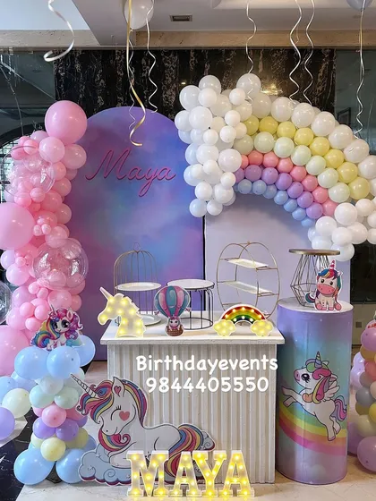 A dreamy unicorn and rainbow themed birthday party. This magical setup features a pastel balloon rainbow, unicorn cutouts, themed props, and light-up marquee letters for the birthday girl's name.