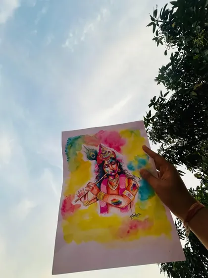 The Krishna watercolor painting held up against the sky. The bright colors of the festival are reflected in the art. Happiest Holi to everyone.