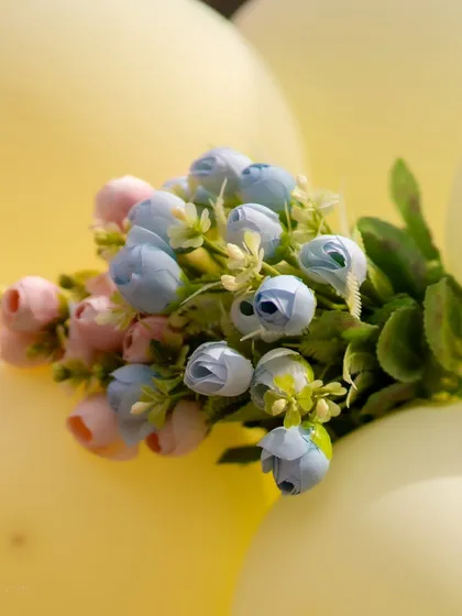 A close-up of tiny artificial flowers used as an accent on a pastel balloon arch. These small details add a delicate and refined touch to the overall decor.