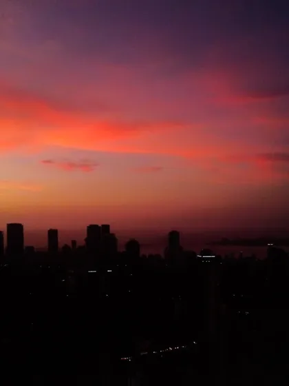 A view of the Mumbai skyline at dusk, with the sky painted in deep shades of purple and red.