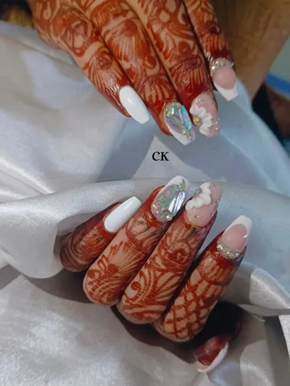 An opulent bridal set featuring a mix of styles: a solid white nail, a French tip with a rhinestone border, a 3D flower, and a stunning shattered glass accent nail.
