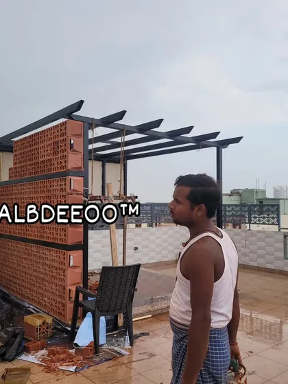 A wider view of the pergola structure during construction. The combination of the modern black MS frame and the earthy, patterned terracotta wall creates a unique and stylish aesthetic right from the build stage.