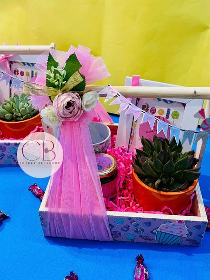 A closer look at our candy-themed return favour baskets. Each one includes a succulent in a colourful pot, a jar of treats, and a personalised thank you card, all decorated with a pink floral touch.