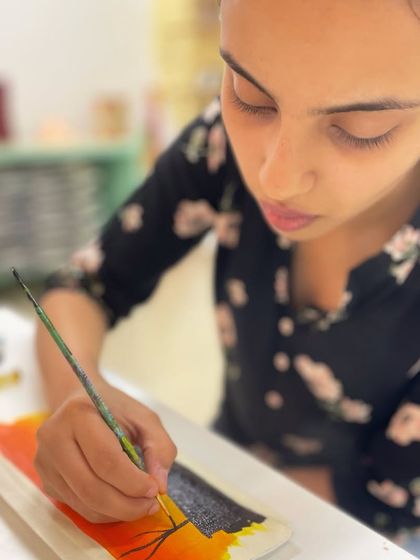 A participant learns the basics of acrylic painting on a canvas pouch, a great beginner project.