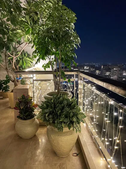 Here’s how I get balconies ready for the festive season. This cozy corner in a Gurgaon high-rise features a mix of tall and bushy plants in custom fibre pots, all lit up with fairy lights for a magical evening vibe.