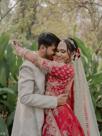 A sweet, candid embrace surrounded by lush greenery, capturing a natural moment of affection on their wedding day.