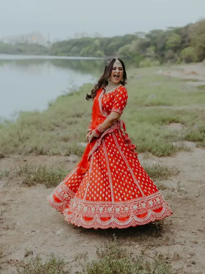 A joyful, candid shot of the bride twirling in her beautiful red lehenga during her pre-wedding shoot.