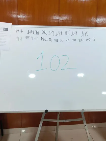 A whiteboard showing a tally of 102. This is from a game I facilitated to visualize data on gender-based violence. Making the numbers visible in this way is a simple but impactful artistic act.