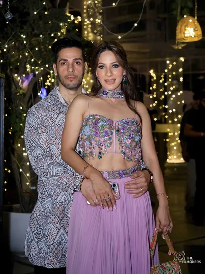 A close-up of the couple, highlighting the intricate print of the man's jacket. It's a great example of a modern festive look for men.