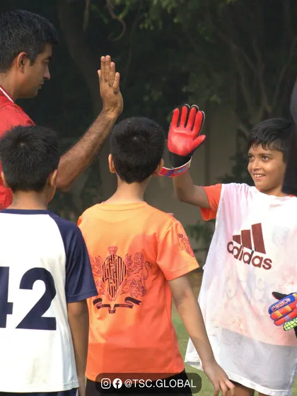 A coach gives a high-five to his young goalkeeper, a moment of encouragement and team spirit.