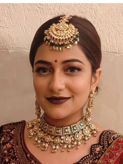 A simple and elegant look featuring a Pachi Kundan choker with green stones and a matching maang tikka.