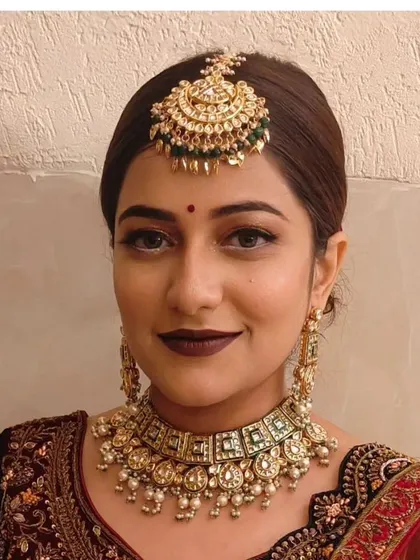 A simple and elegant look featuring a Pachi Kundan choker with green stones and a matching maang tikka.
