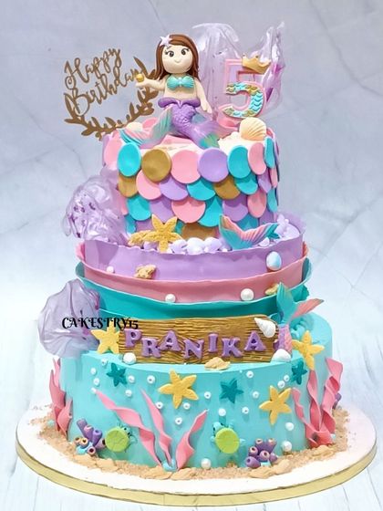 A spectacular three-tier mermaid-themed cake for a 5th birthday. This 5kg chocolate cake features a fondant mermaid, shimmering fish scales, and an abundance of sea creatures.